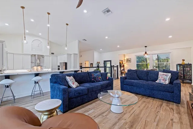 a living room with furniture kitchen view and a wooden floor