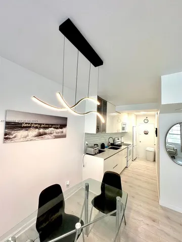 a kitchen with stainless steel appliances a stove a refrigerator a sink a dining table and chairs with wooden floor