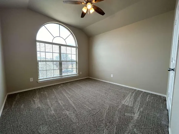 an empty room with chandelier fan and windows
