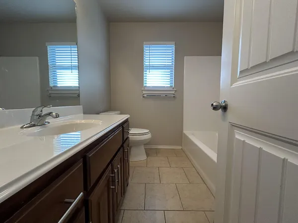 a bathroom with a granite countertop sink a toilet a mirror and a tub