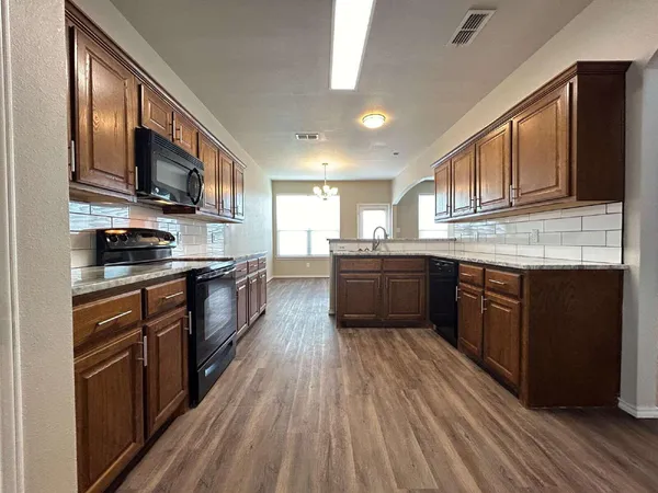 a large kitchen with stainless steel appliances granite countertop a stove a sink dishwasher and a refrigerator