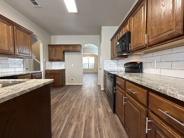 a kitchen with stainless steel appliances granite countertop wooden cabinets a sink dishwasher a stove and a refrigerator