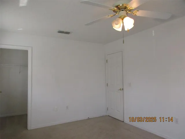 an empty room with a chandelier fan and a window