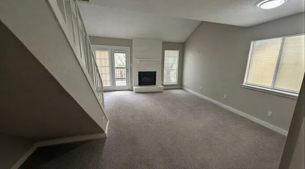 a view of an empty room with a fireplace and a window