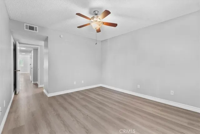 an empty room with wooden floor and a ceiling fan