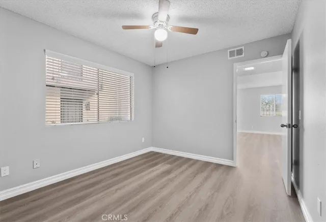 a view of empty room with wooden floor and fan