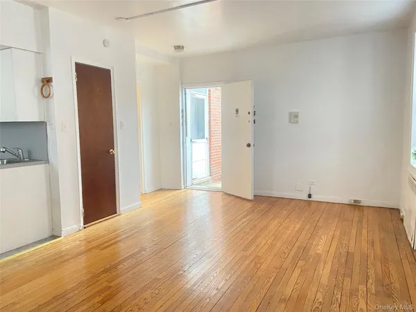 a view of an empty room with wooden floor and a bathroom