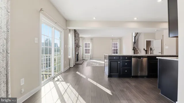 a living room with stainless steel appliances kitchen island granite countertop a refrigerator and a sink