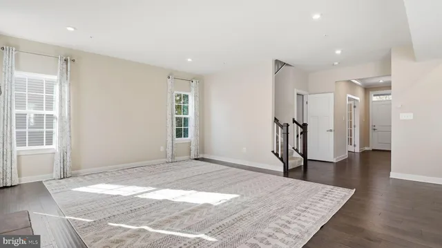 an empty room with wooden floor and a rug