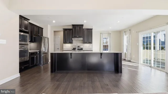 a kitchen with stainless steel appliances granite countertop a stove a refrigerator a sink a oven with wooden floors and cabinets