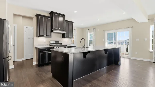 a kitchen with stainless steel appliances granite countertop a refrigerator and a stove top oven