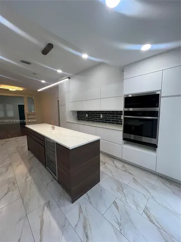 a large white kitchen with stainless steel appliances and a cabinets