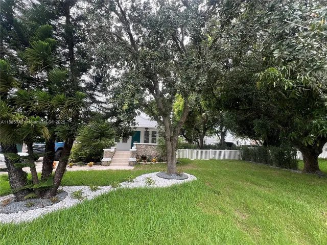 a view of a house with a big yard potted plants and large tree