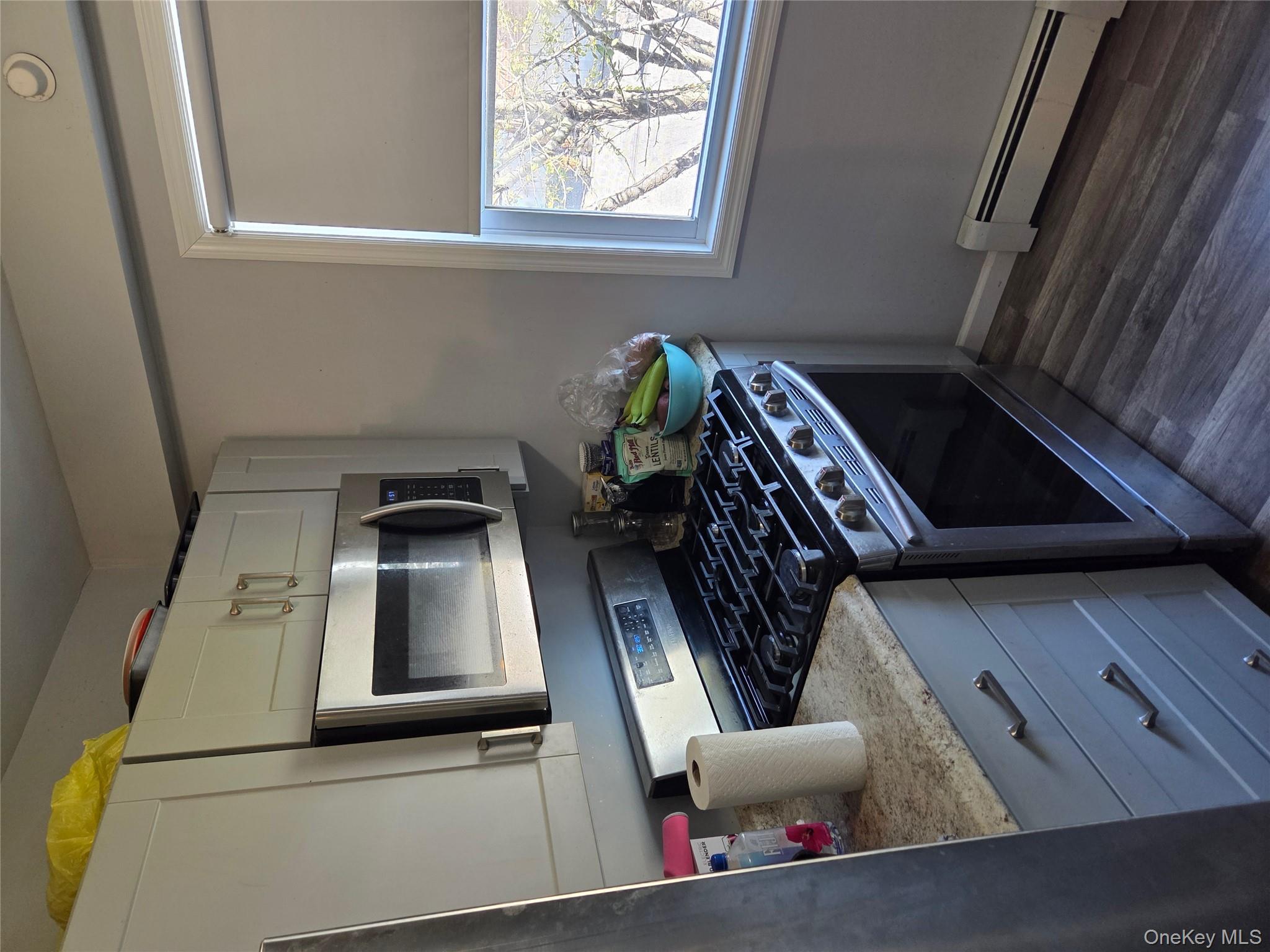 3095 Mullan Place Bronx, NY 10465 - Photo 8 of 12 Kitchen with stainless steel range, a baseboard radiator, white microwave, dark wood-style floors, and refrigerator