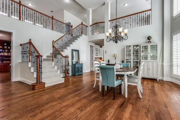 a dining room with wooden floor a chandelier a wooden table and chairs
