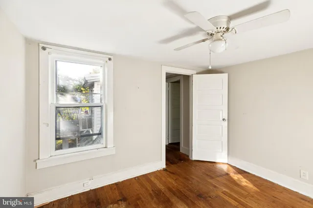 a view of an empty room with a window and wooden floor