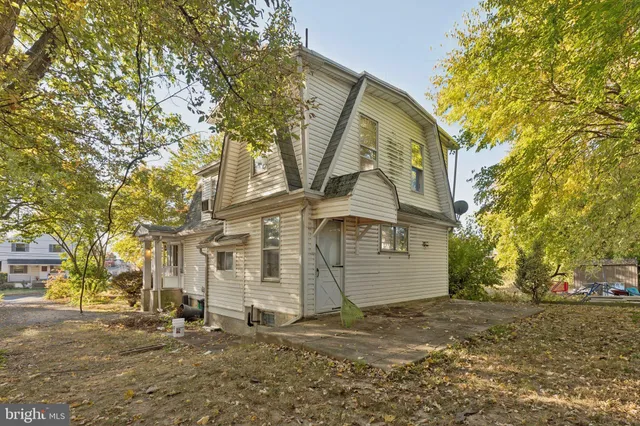 a view of a white house with a large tree