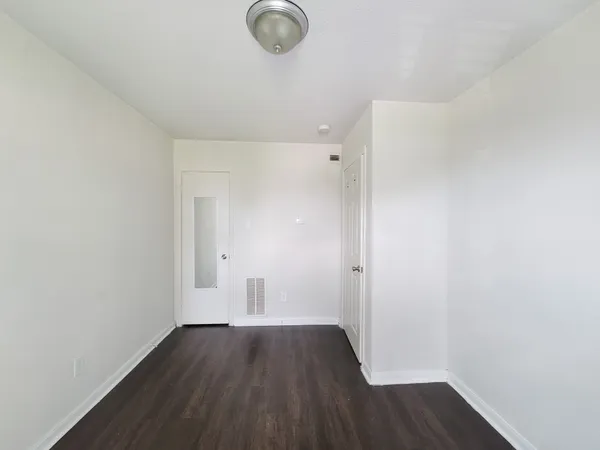 a view of a room with wooden floor and white walls