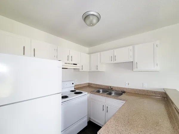 a kitchen with a sink a stove and white cabinets