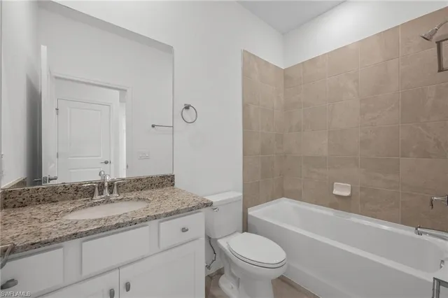 a bathroom with a granite countertop sink a toilet and bathtub