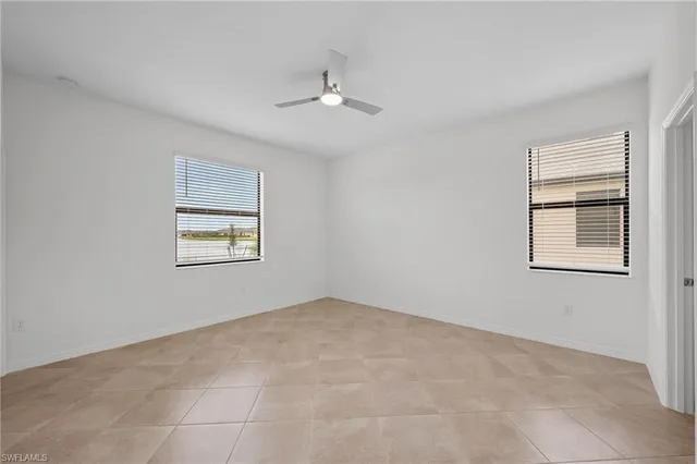 an empty room with windows and fan