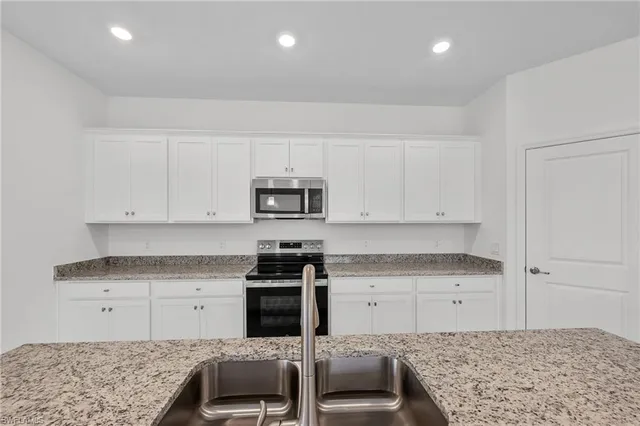 a large kitchen with granite countertop a large counter top stainless steel appliances and cabinets