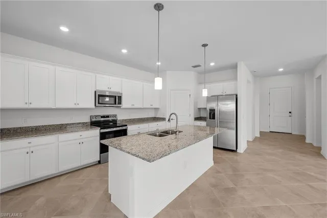 a kitchen with kitchen island a sink stainless steel appliances and white cabinets