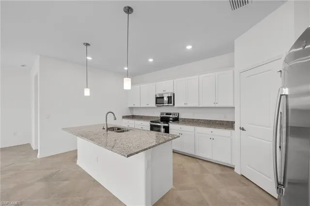 a kitchen with a sink a center island stainless steel appliances and cabinets