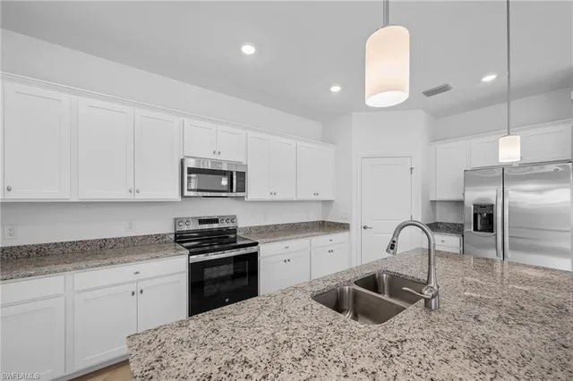 a kitchen with granite countertop a sink stainless steel appliances and white cabinets