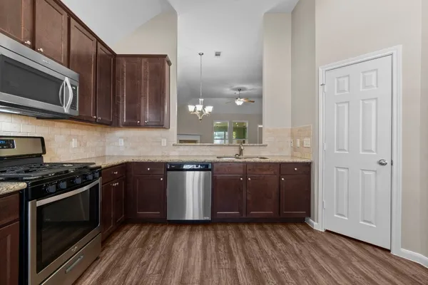 a kitchen with stainless steel appliances granite countertop wooden cabinets stove top oven and sink