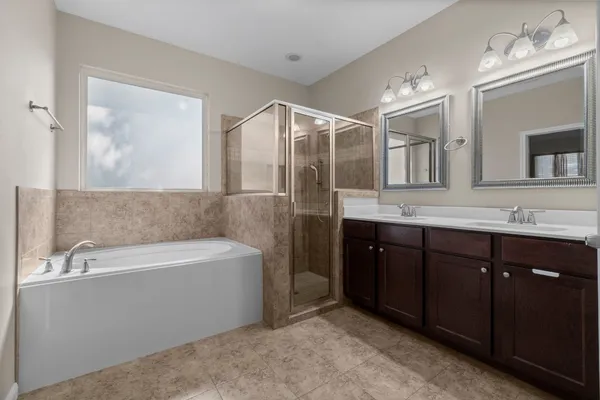 a spacious bathroom with a tub double sink and mirror