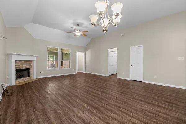 a view of an empty room with wooden floor and fireplace