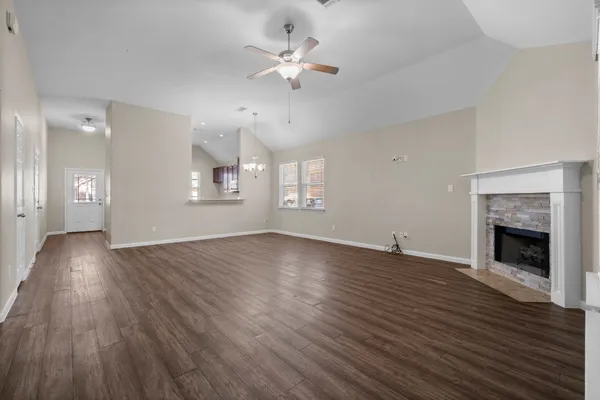 a view of an empty room with wooden floor fireplace and a window