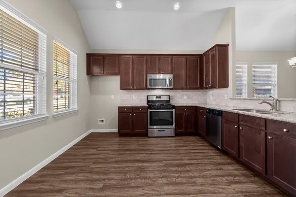 a kitchen with stainless steel appliances granite countertop a stove a sink and a microwave