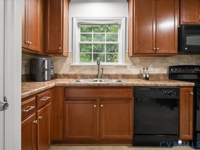 a kitchen with granite countertop cabinets stainless steel appliances a sink and a window
