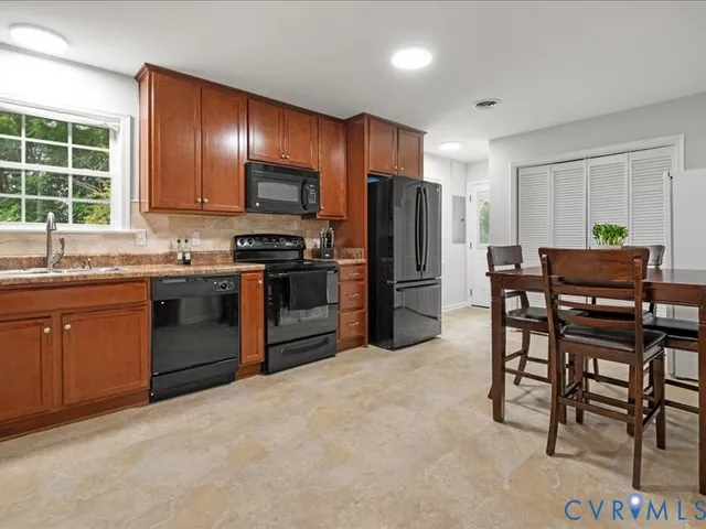 a kitchen with stainless steel appliances granite countertop a stove a sink dishwasher a refrigerator and a microwave oven with wooden floor