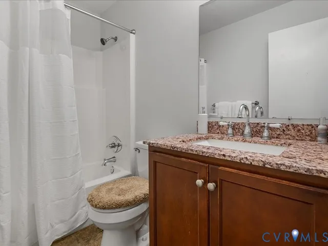 a bathroom with a granite countertop sink a toilet and shower
