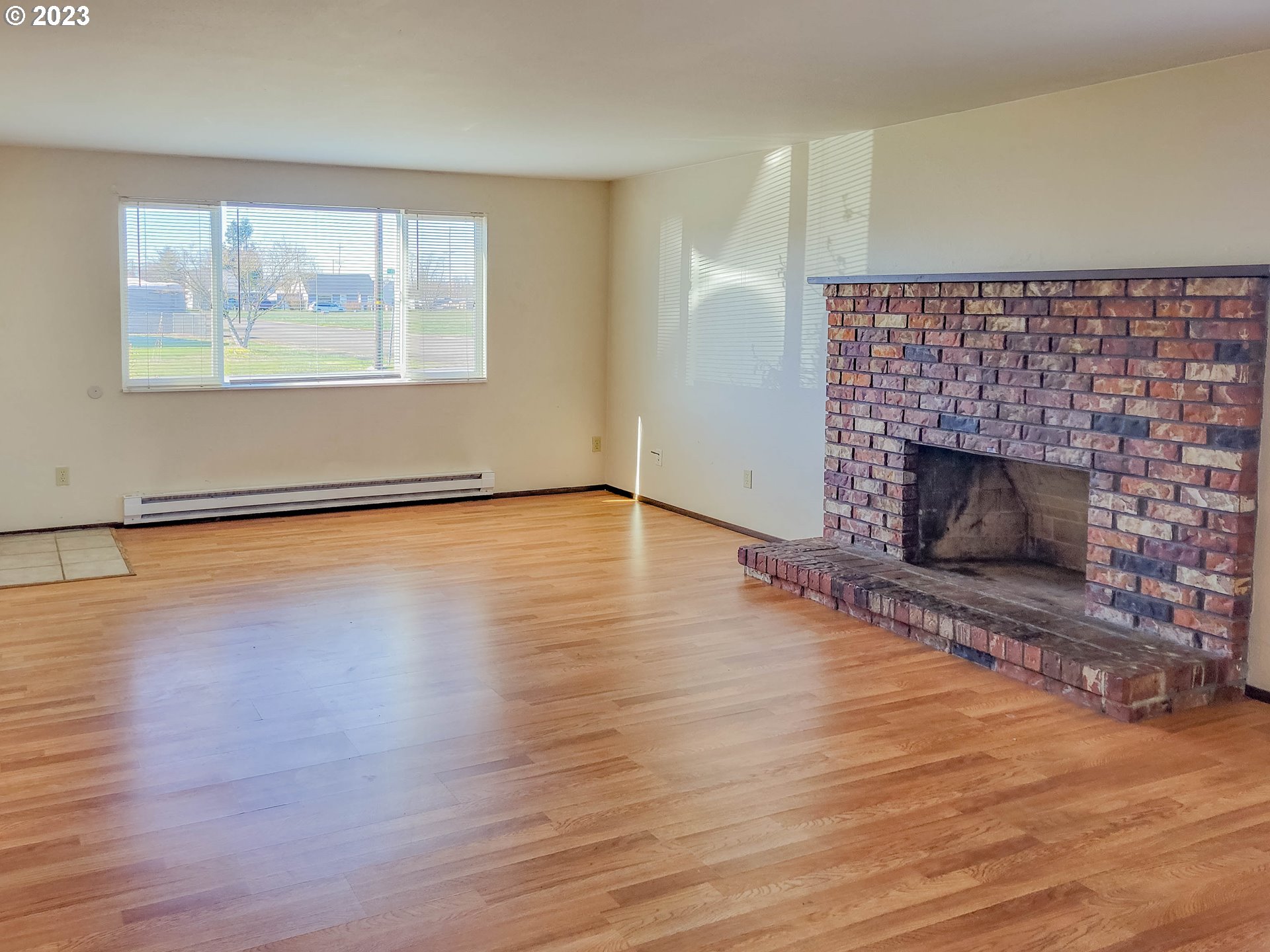 215 South 10th Street Lebanon, OR 97355 - Photo 6 of 9 an empty room with wooden floor fireplace and windows