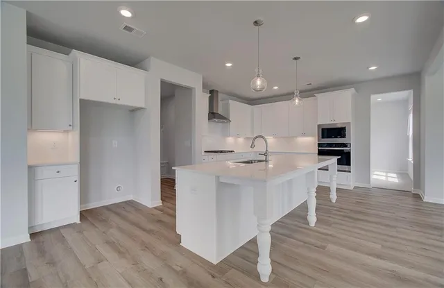 a large white kitchen with wooden floor and stainless steel appliances