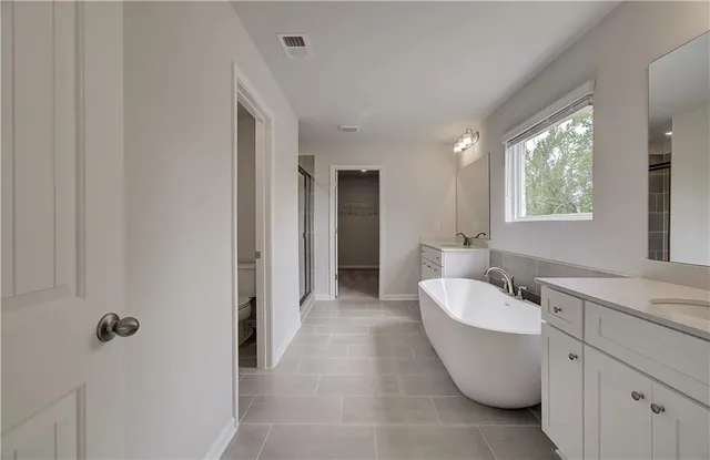 a spacious bathroom with a double vanity sink a mirror and a bathtub