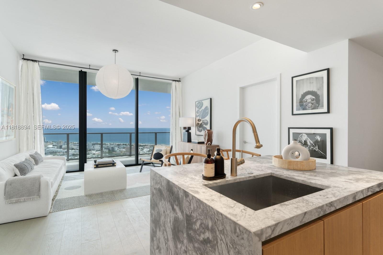 500 Alton Road, Unit 4004 Miami Beach, FL 33139 - Photo 6 of 26 a kitchen with a stove a faucet a sink and a living room with couches