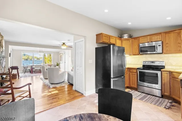 a living room with stainless steel appliances furniture a refrigerator and a kitchen view