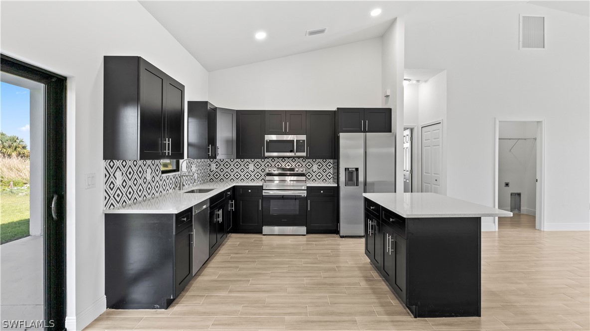 422 Progress Avenue Lehigh Acres, FL 33974 - Photo 11 of 35 a large kitchen with a counter top space a sink stainless steel appliances and cabinets