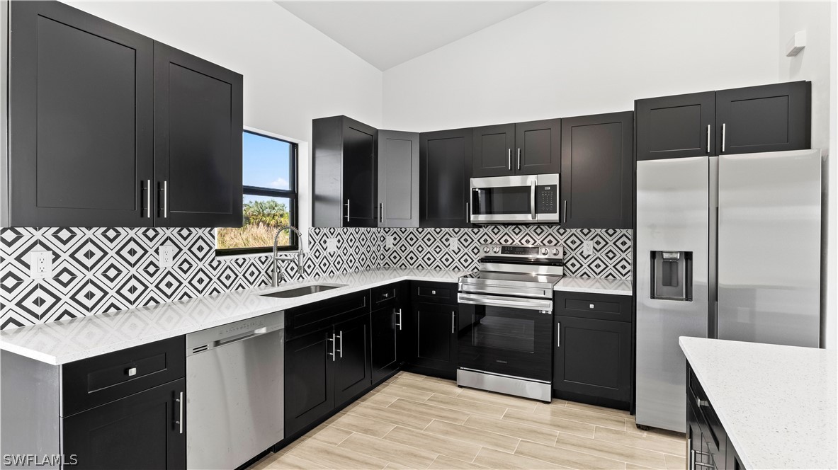422 Progress Avenue Lehigh Acres, FL 33974 - Photo 12 of 35 a kitchen with stainless steel appliances granite countertop a sink stove and refrigerator