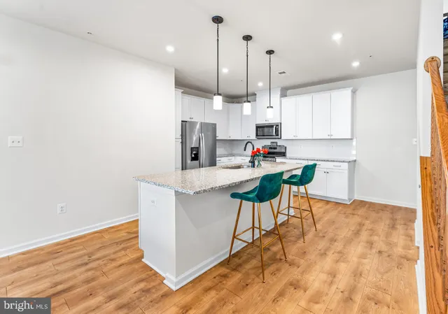 a kitchen with kitchen island a stove a refrigerator a sink and chairs