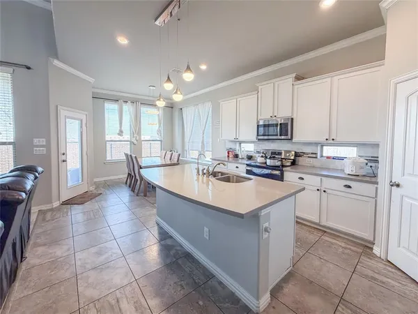 a kitchen with kitchen island granite countertop a sink a stove and refrigerator