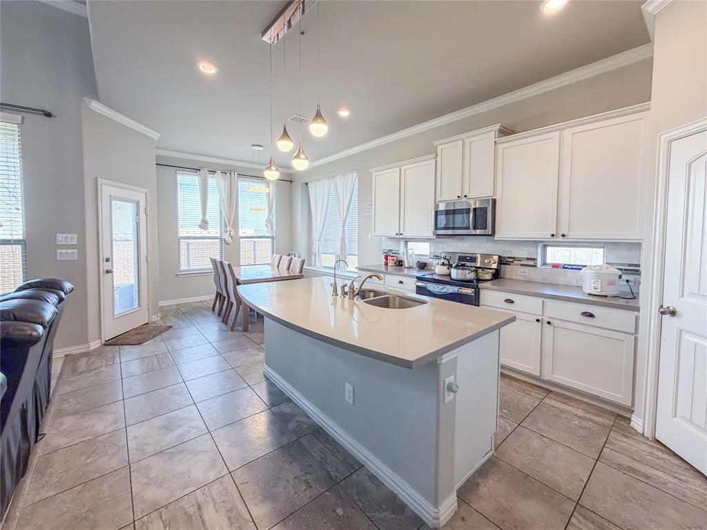 328 Callaghan Drive Fate, TX 75189 - Photo 20 of 37 a kitchen with kitchen island granite countertop a sink counter top space appliances and cabinets