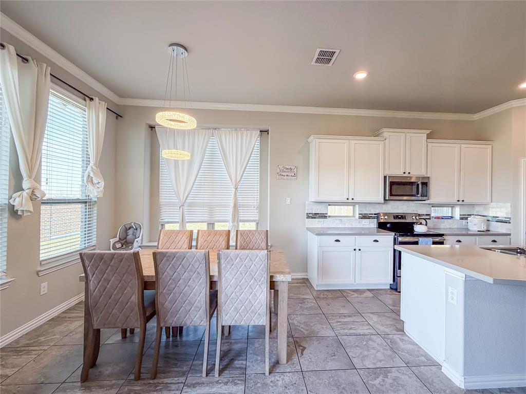 328 Callaghan Drive Fate, TX 75189 - Photo 25 of 37 a kitchen with a stove a sink a dining table and chairs