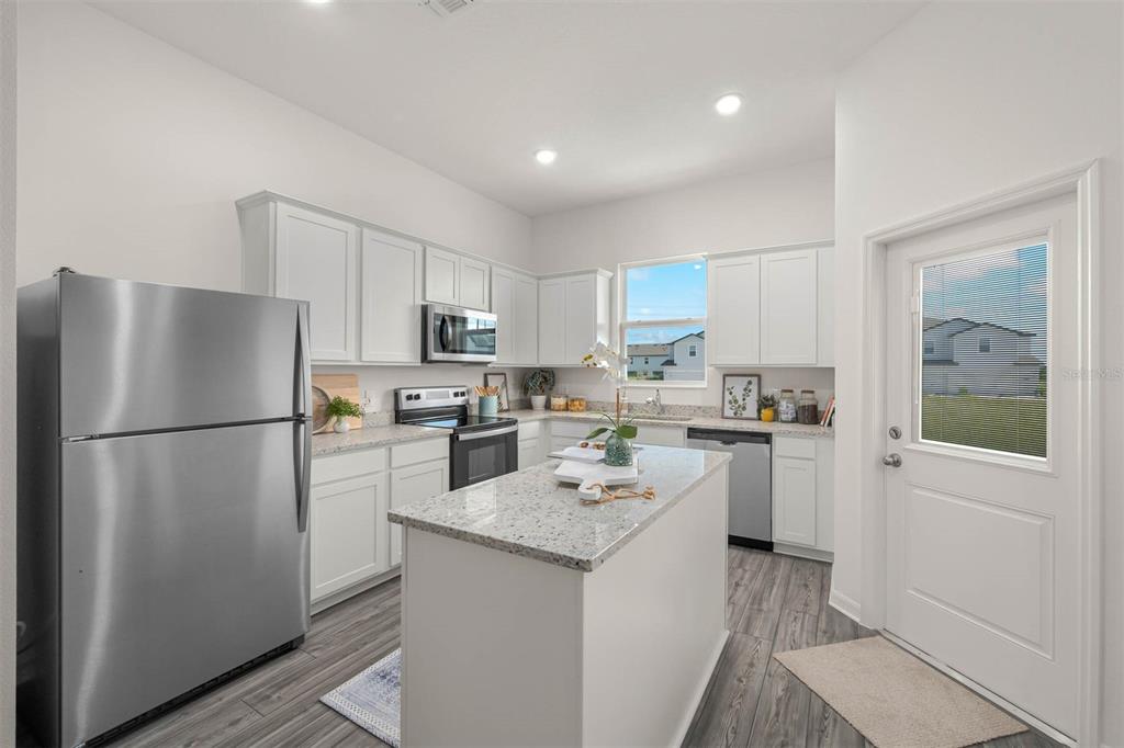 721 Poppy Lane Dundee, FL 33838 - Photo 13 of 26 a kitchen with a refrigerator a sink a stove a microwave and cabinets