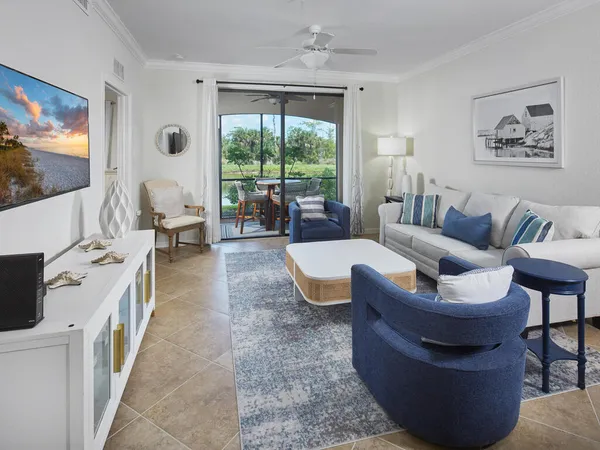 a living room with furniture a flat screen tv and a floor to ceiling window